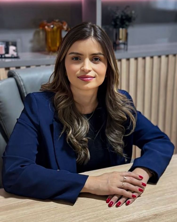 Mary Hellen Rodrigues de Abreu, de blazer azul-marinho, sentada à mesa no escritório